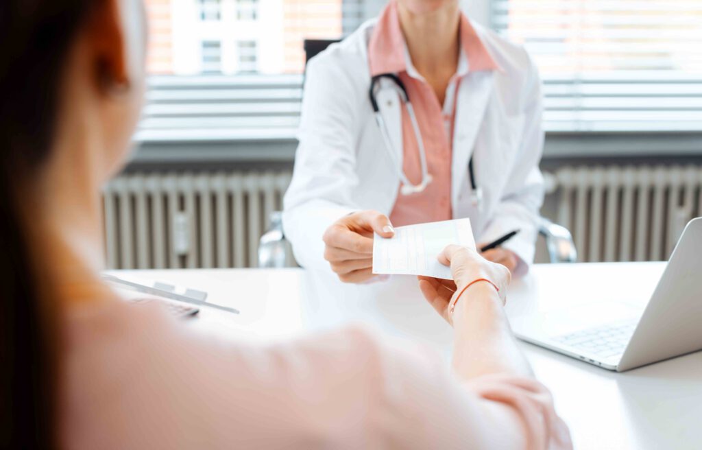 A doctor handing a prescription to a woman in her office